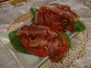 Laughing Cow garlic and herb cheese spread on Wasa crisp bread topped with raw spinach, tomatoes and bacon. 